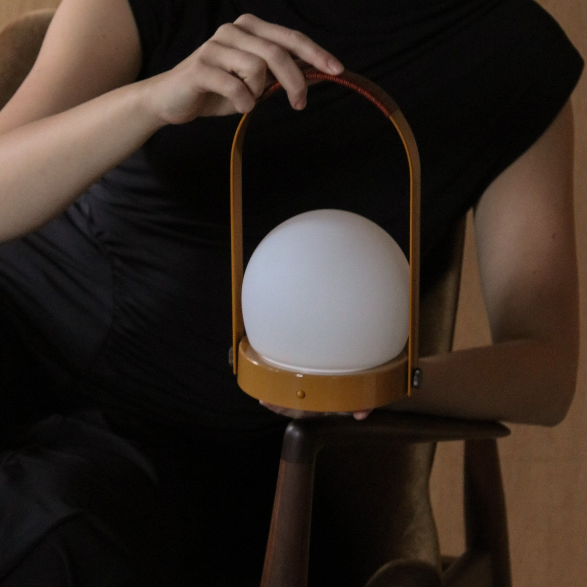 Audo Copenhagen Carrie LED Lamp Golden Brown Leather held on a chair - KANSO#Color_Golden Brown Leather