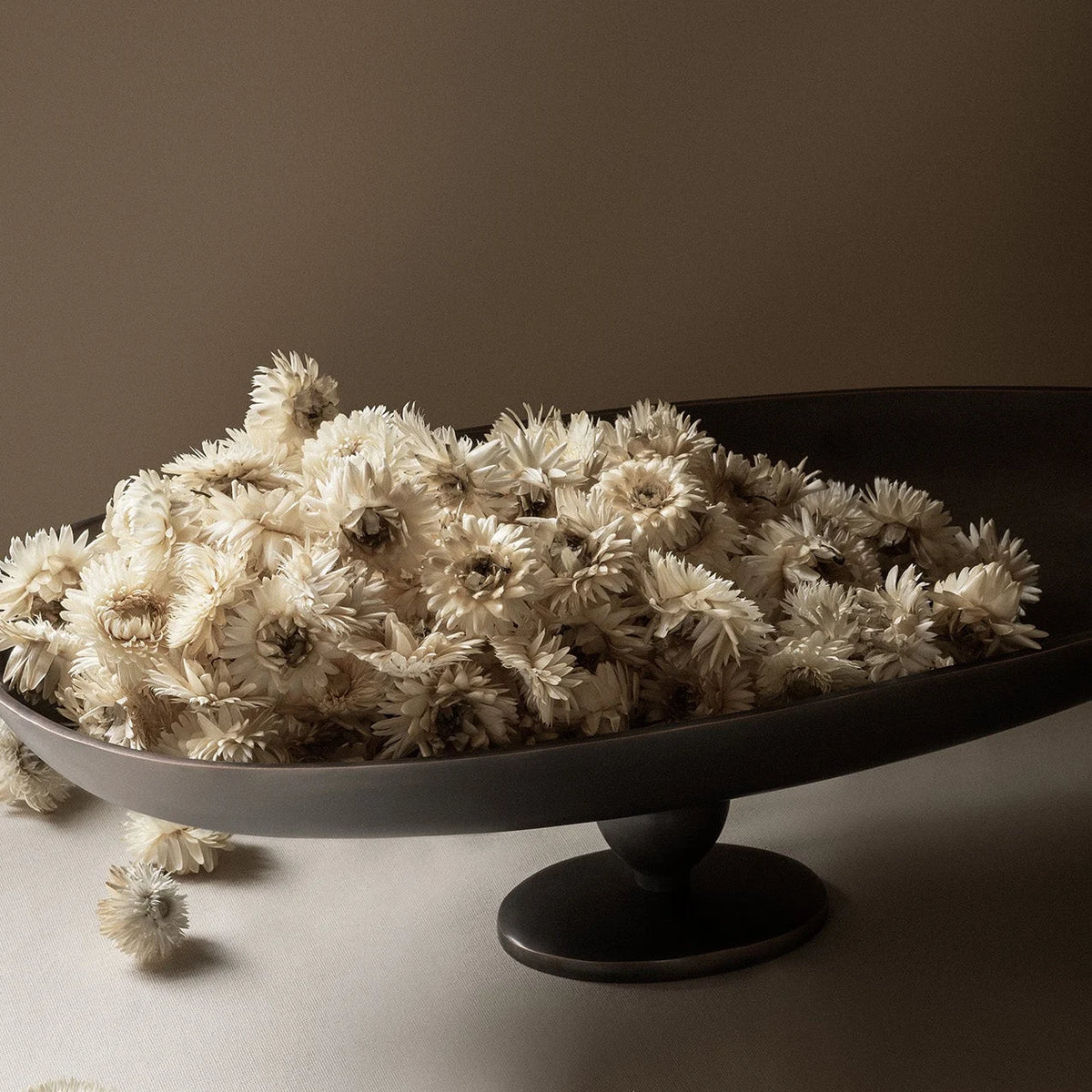 Audo Copenhagen Pavot Centerpiece on a low stone plinth by a sofa - KANSO