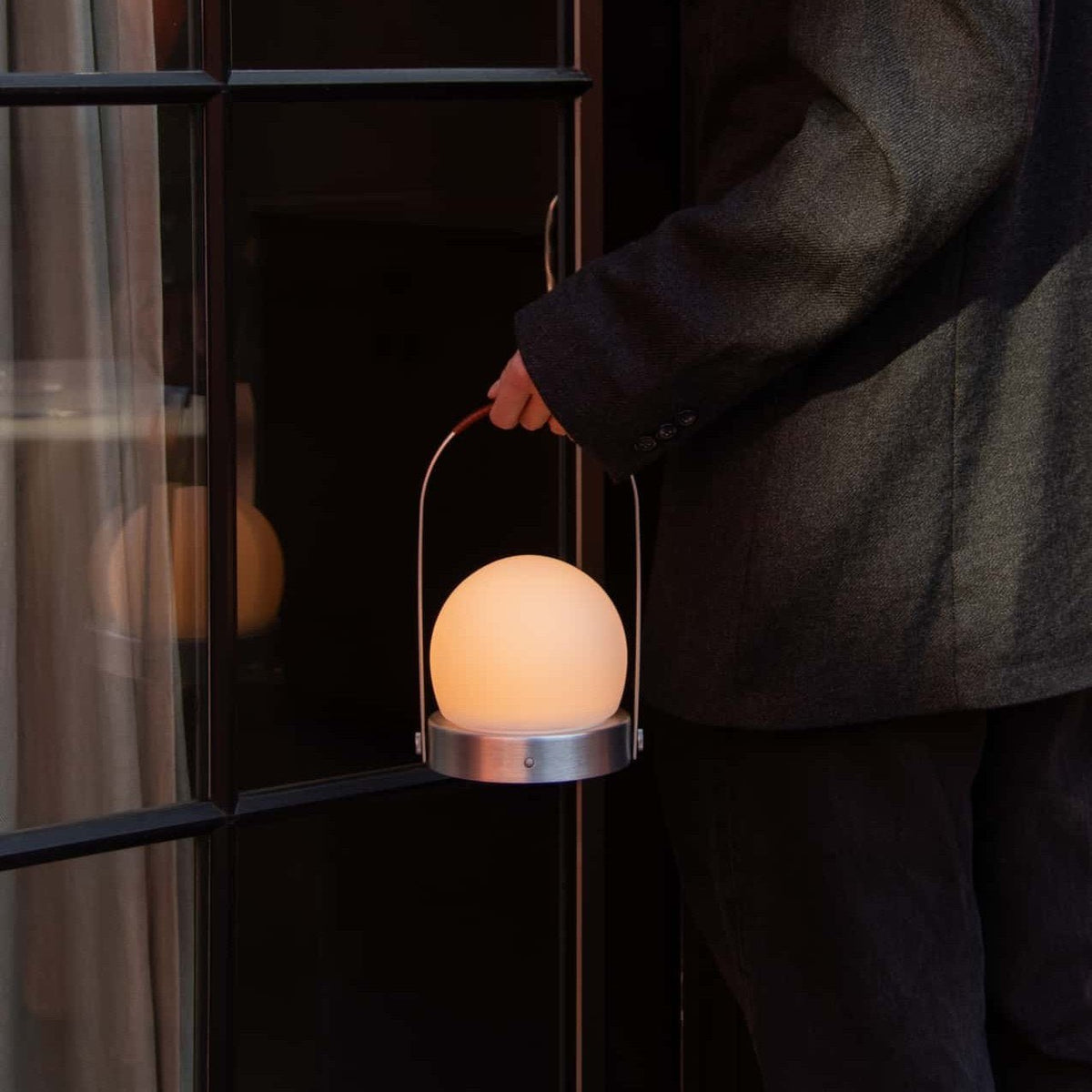 Audo Copenhagen Carrie LED Lamp Brushed Aluminium Leather carried through a doorway - KANSO#Color_Brushed Aluminium Leather