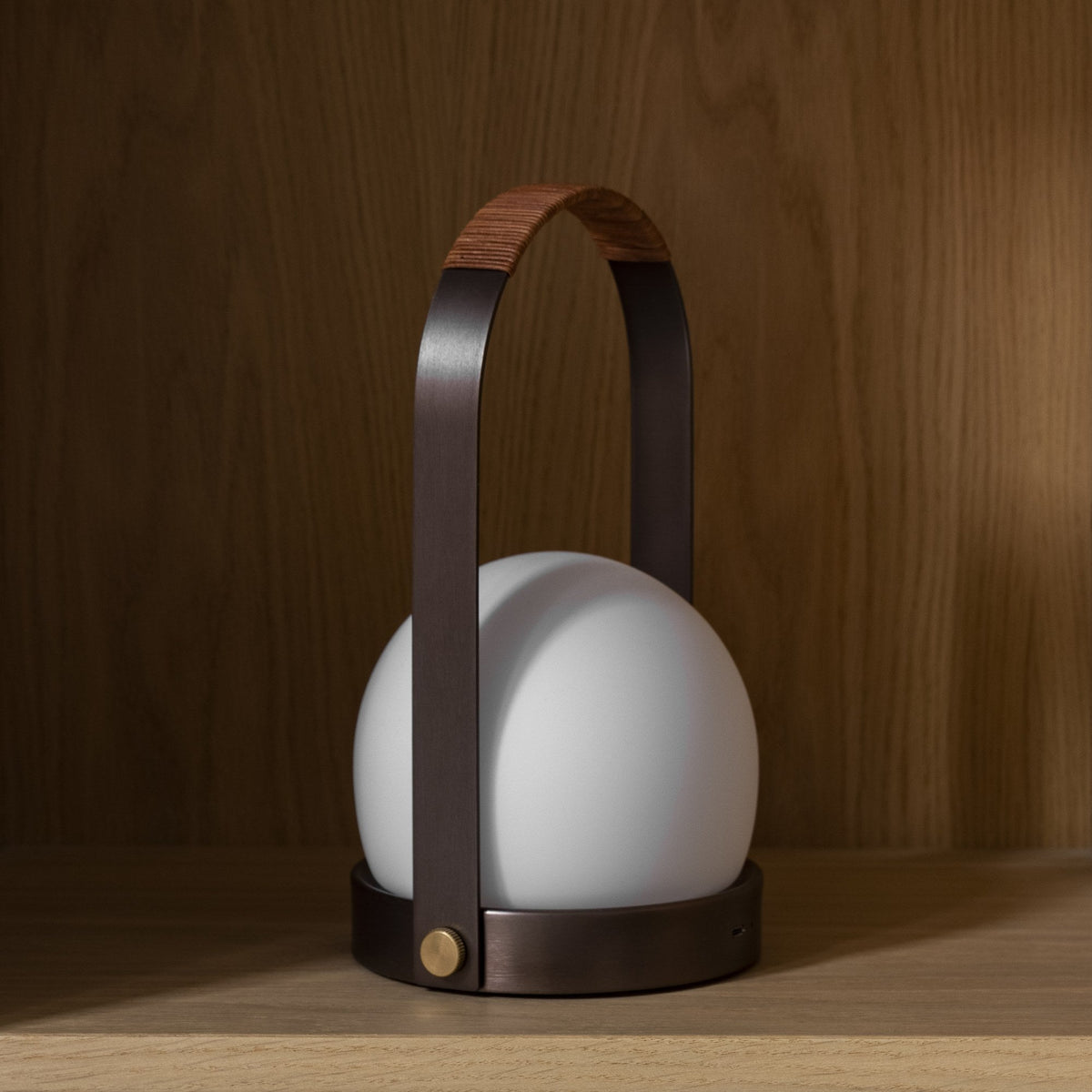 Audo Copenhagen Carrie LED Lamp Bronzed Brass in front of an oak wall - KANSO#Color_Bronzed Brass