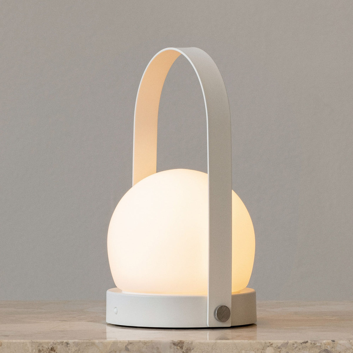 Audo Copenhagen Carrie LED Lamp White lit on a stone shelf - KANSO#Color_White